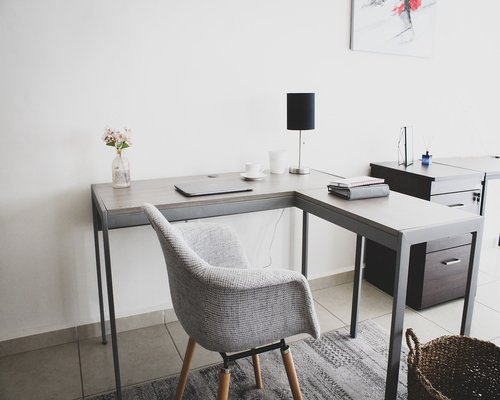 A well-organized wooden desk with a notebook, plants, and natural light