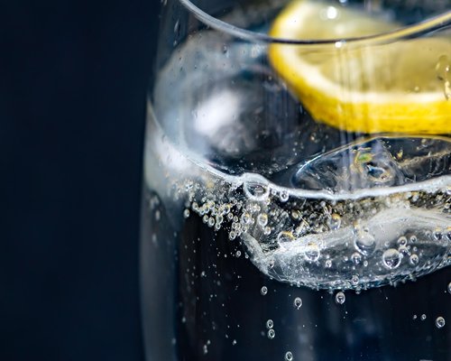A glass of fresh water with lemon slices next to a small cup of dark coffee